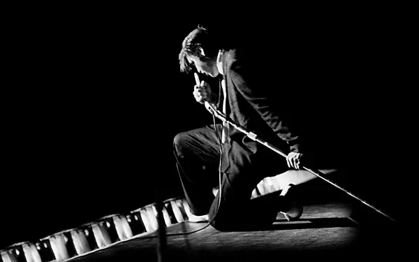 Black and white HD desktop wallpaper of Elvis Presley performing rock & roll music, captured mid-song with dynamic stage presence and vintage microphone.