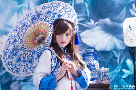 A woman in a traditional Taiwanese costume holds a decorative umbrella, set against a backdrop of blue floral patterns in a vibrant 4K Ultra HD wallpaper.