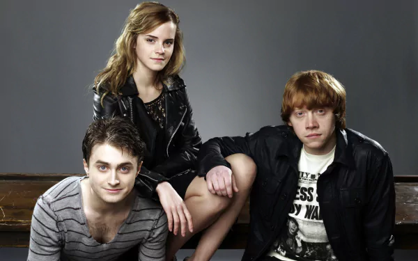Daniel Radcliffe, Rupert Grint, and Emma Watson pose together in a stylish HD wallpaper, showcasing their iconic status as beloved actors from the Harry Potter series.