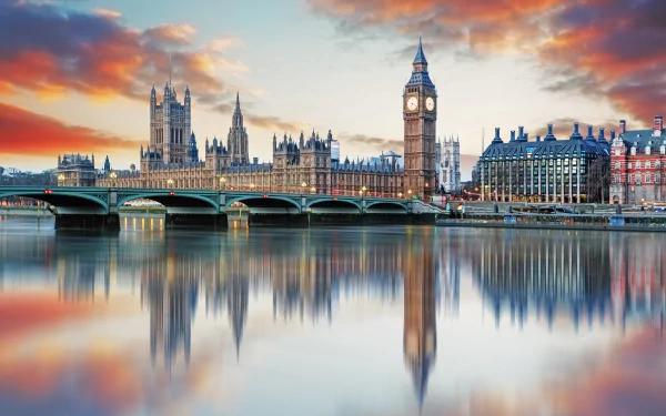 4K Ultra HD image of Buckingham Palace and the Palace of Westminster, with Big Ben and Westminster Bridge reflected in the River Thames under a vibrant sunset sky.
