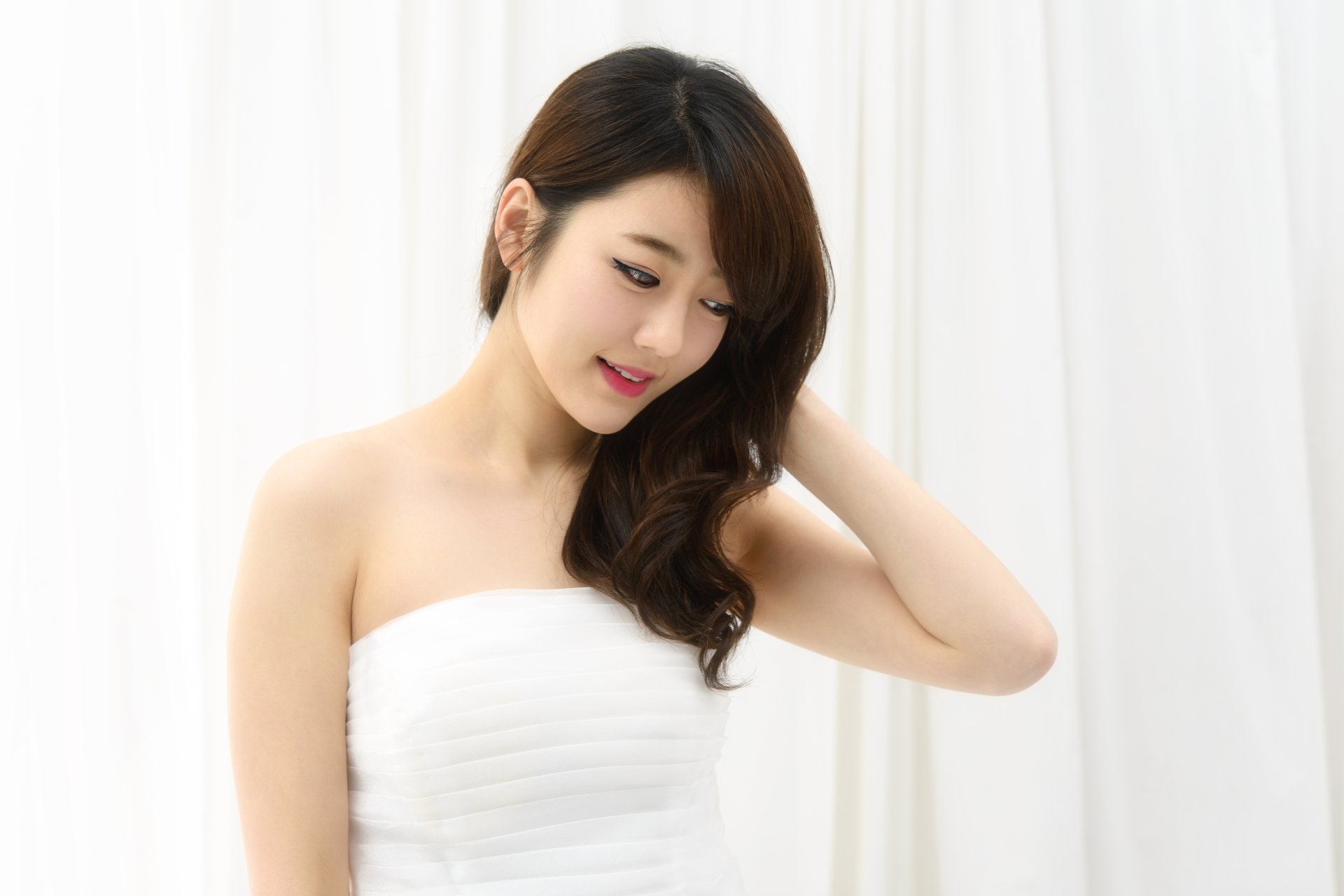HD desktop wallpaper featuring an Asian woman model in a white dress, standing against a softly lit white background with a serene expression.