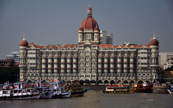 The Taj Mahal Palace Hotel in Mumbai, India, showcases stunning architecture near the Gateway of India, surrounded by boats on the harbor. A captivating view of Maharashtra's landmarks.