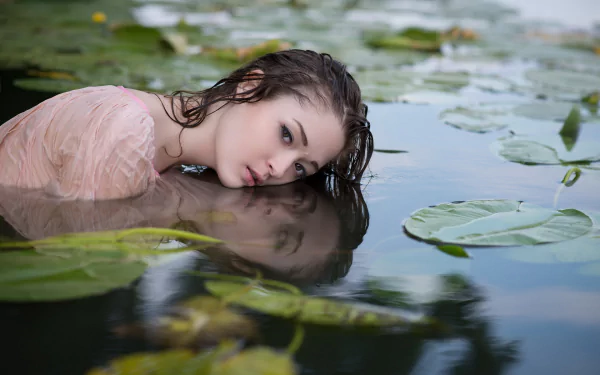 HD wallpaper featuring a beautiful woman with wet hair, half-submerged in water surrounded by lily pads.