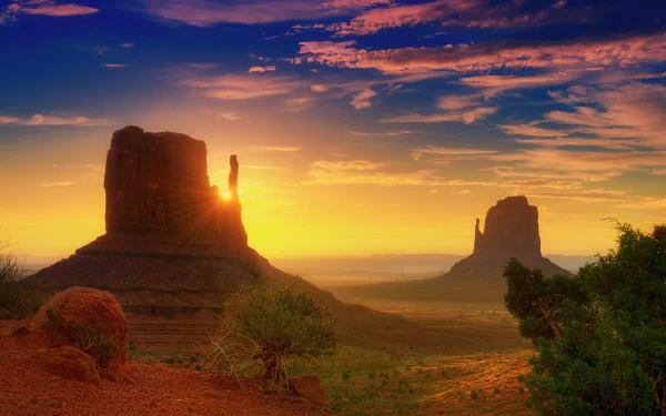 Stunning Arizona sunrise illuminating Monument Valley, with vibrant sunbeams spreading across the expansive desert sky, showcasing the beauty of nature in Utah. HD wallpaper.