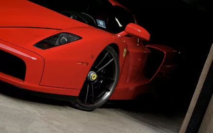 HD desktop wallpaper featuring a striking red Ferrari Enzo sports car with sleek design and black rims, captured in a low-angle close-up shot.