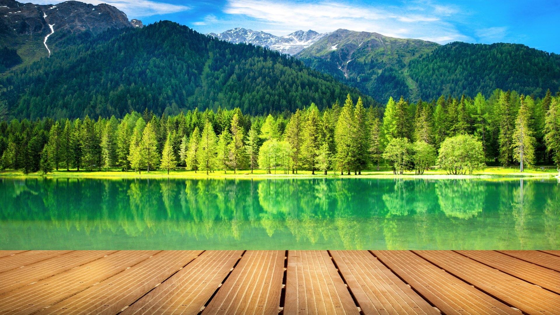 HD PC desktop wallpaper featuring a serene river with clear green water, surrounded by dense forest and distant mountains under a bright blue sky.