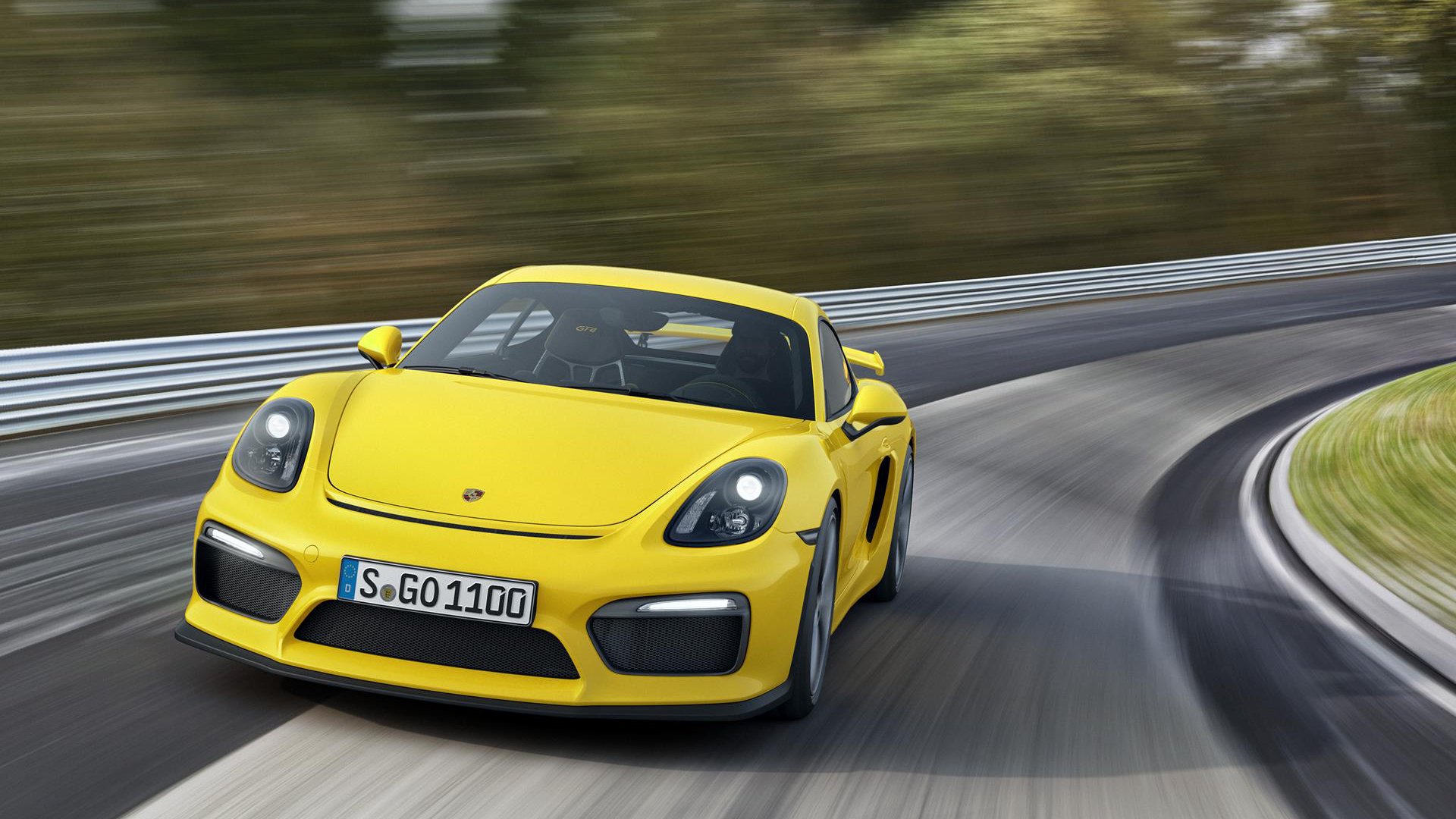 Yellow Porsche Cayman GT4 racing on a curved track, captured in high-definition, showcasing the sleek design of the sports car in motion.