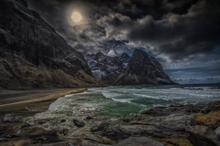 Dramatic coastline of Kvalvika, Lofoten Islands, Norway, features rugged mountains and turbulent seas under an atmospheric sky, creating a stunning natural landscape.