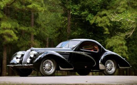 A sleek black Talbot-Lago vintage car parked on a road, surrounded by lush green trees, captured in stunning 4K Ultra HD quality.