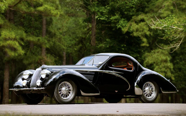 A sleek black Talbot-Lago vintage car parked on a road, surrounded by lush green trees, captured in stunning 4K Ultra HD quality.