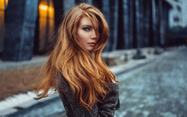 HD desktop wallpaper featuring a redheaded woman, tagged as a model, standing on a cobblestone street with a dark, blurred urban background.