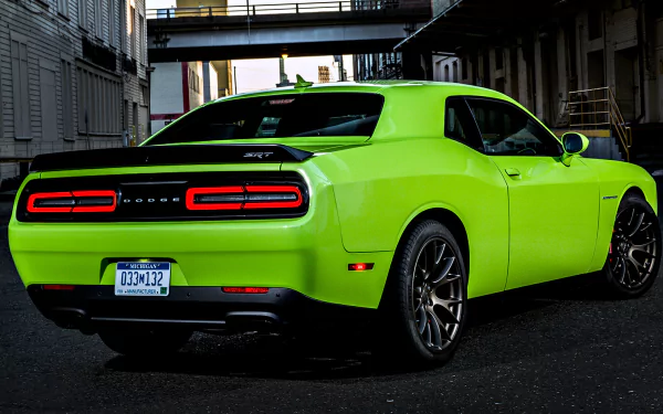 A vibrant green Dodge Challenger SRT Hellcat is parked in an urban alley, showcasing its sleek design and distinctive taillights in this HD desktop wallpaper.