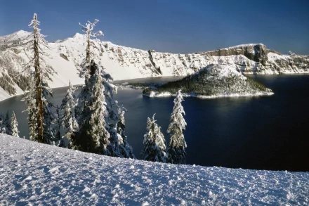 A stunning winter view of Crater Lake National Park in Oregon, featuring snow-covered trees and the serene, deep blue Crater Lake, captured in HD for a beautiful desktop wallpaper and background.