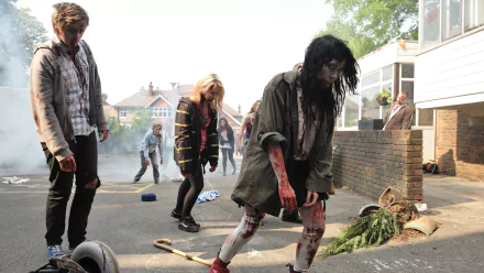 HD PC desktop wallpaper of the movie Cockneys vs Zombies: bloodied zombies shuffling down a suburban street amid overturned bikes and debris.