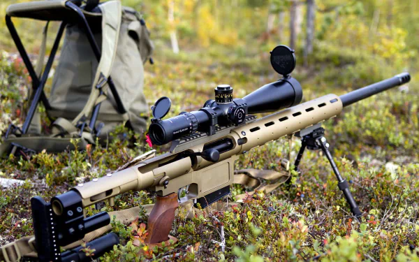 A detailed sniper rifle rests on the ground surrounded by greenery, with a backpack and chair in the background, providing a rugged outdoor scene for this HD desktop wallpaper.