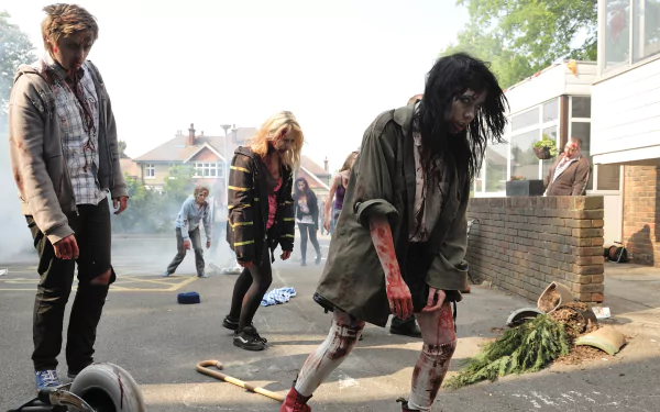 HD PC desktop wallpaper of the movie Cockneys vs Zombies: bloodied zombies shuffling down a suburban street amid overturned bikes and debris.