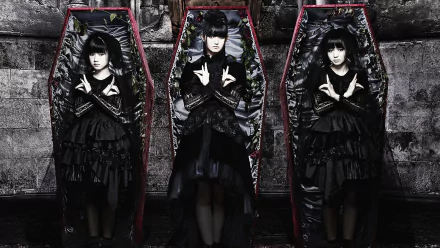 Three Japanese metal idols in dark, layered outfits pose inside ornate coffins, embodying the heavy metal aesthetic of Babymetal. A striking HD desktop wallpaper that captures their unique style.