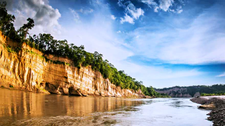 A serene landscape of a river in Argentina, framed by lush greenery and dramatic cliffs beneath a bright sky. This stunning image captures the essence of nature and earth's beauty.