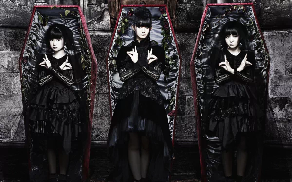 Three Japanese metal idols in dark, layered outfits pose inside ornate coffins, embodying the heavy metal aesthetic of Babymetal. A striking HD desktop wallpaper that captures their unique style.