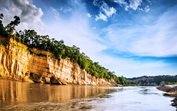 A serene landscape of a river in Argentina, framed by lush greenery and dramatic cliffs beneath a bright sky. This stunning image captures the essence of nature and earth's beauty.