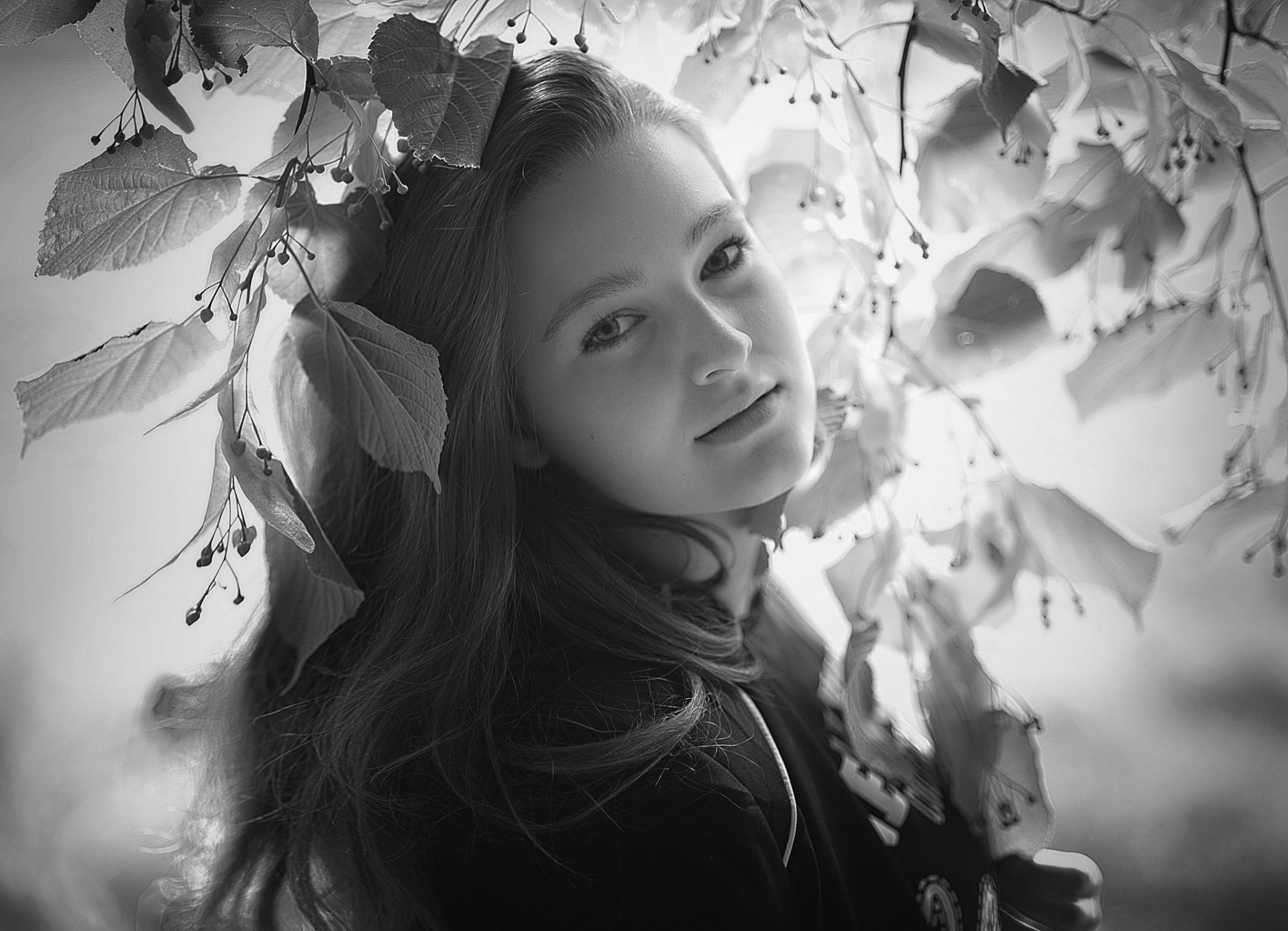 Black and white HD desktop wallpaper featuring a model woman surrounded by softly blurred leaves, creating a delicate bokeh effect.