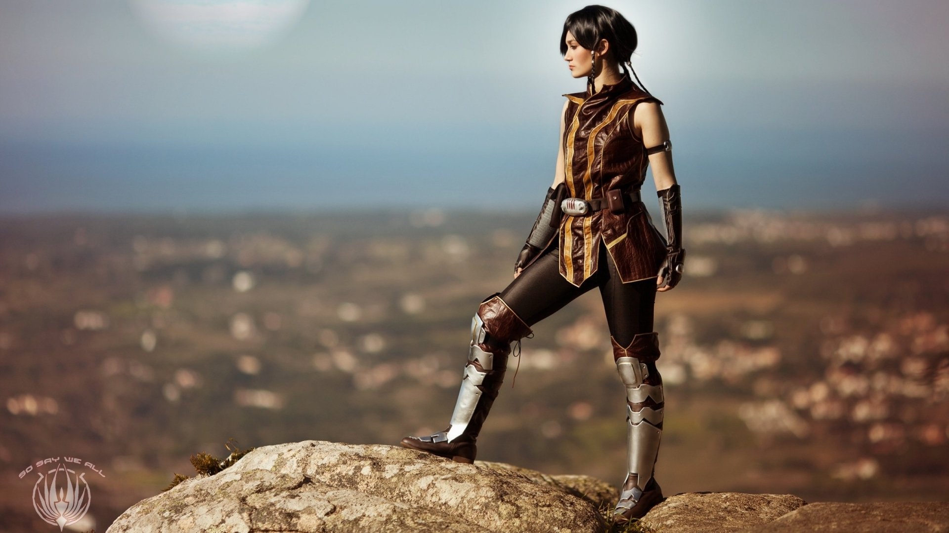 A woman in striking cosplay stands confidently on a rocky outcrop, overlooking a scenic landscape. This HD image serves as an engaging desktop wallpaper and background.