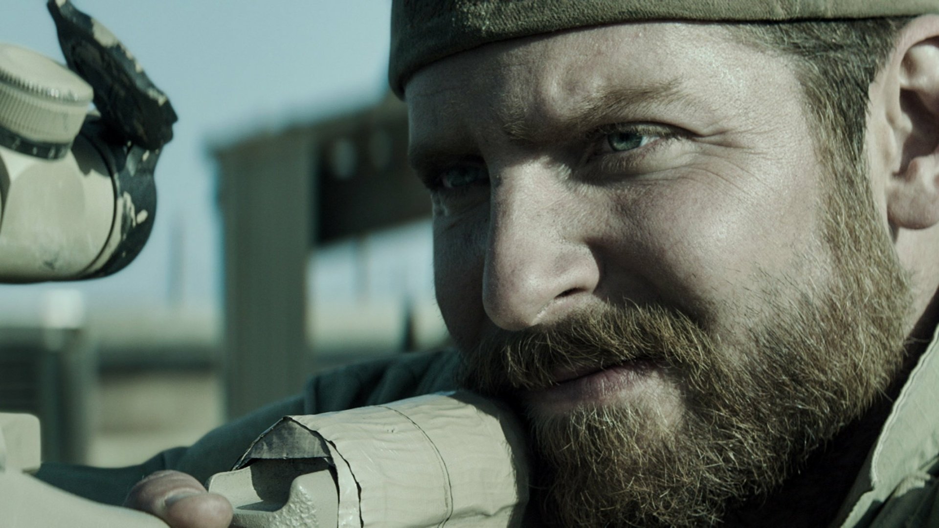 A high-definition desktop wallpaper featuring a close-up of a character from American Sniper, focusing intensely through a rifle's scope.