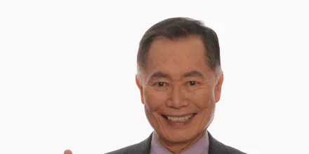 HD desktop wallpaper featuring a smiling man in a grey suit against a plain background.