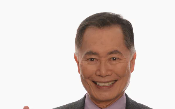 HD desktop wallpaper featuring a smiling man in a grey suit against a plain background.