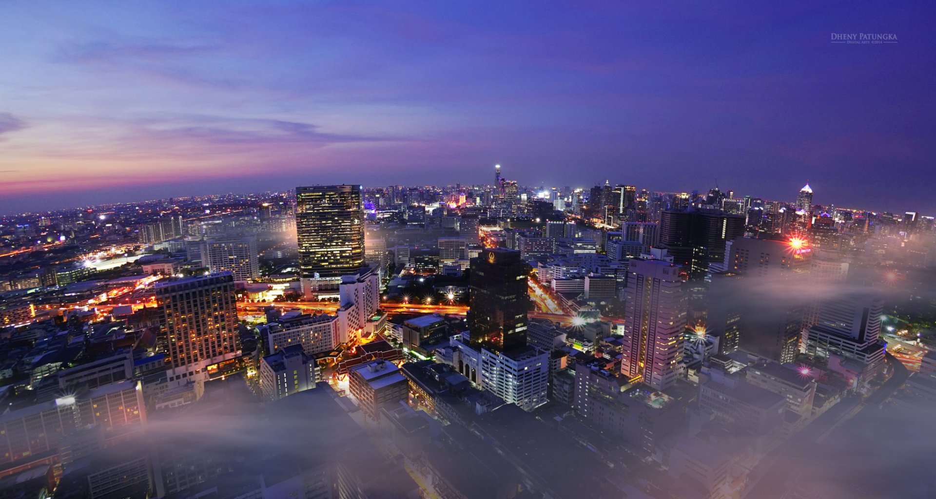 Nighttime cityscape of Bangkok, Thailand, showcasing vibrant city lights and dense urban buildings under a clear, dark sky in an HD PC desktop wallpaper.