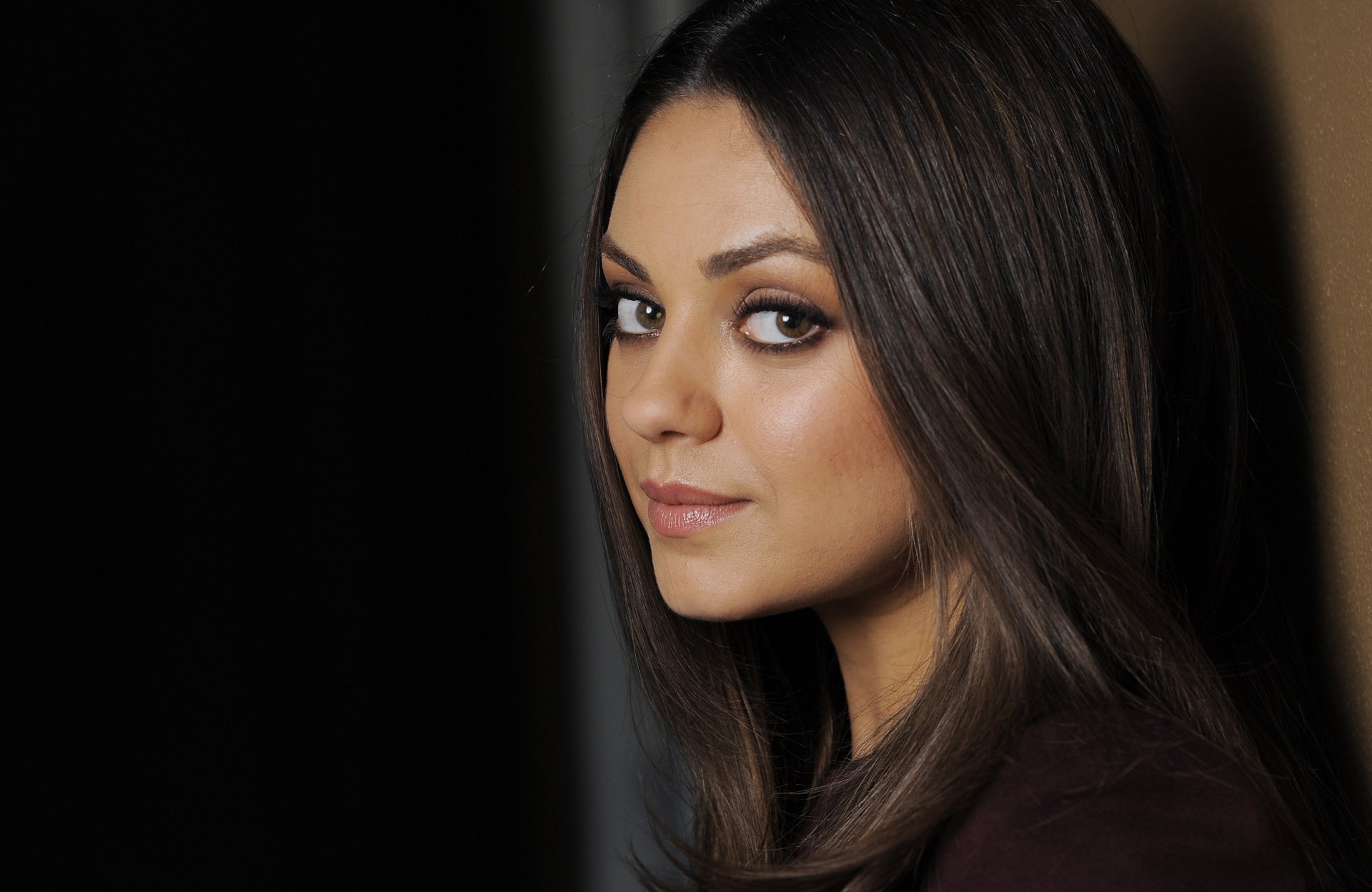 HD desktop wallpaper featuring a close-up portrait of celebrity Mila Kunis with soft lighting and a neutral background.