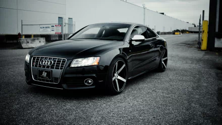 Black Audi S5 parked on an industrial lot, HD PC desktop wallpaper background showcasing sleek lines and alloy wheels.