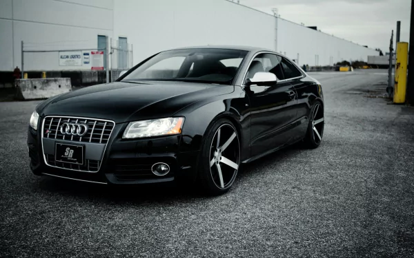 Black Audi S5 parked on an industrial lot, HD PC desktop wallpaper background showcasing sleek lines and alloy wheels.