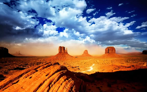 Expansive desert landscape of Monument Valley featuring majestic rock formations under a dramatic sky filled with clouds, creating a stunning nature backdrop.