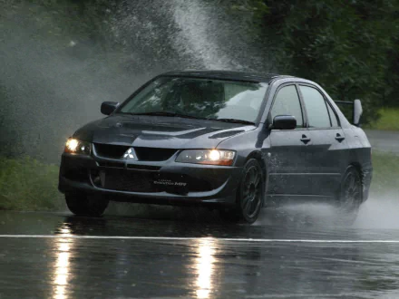 A Mitsubishi Lancer Evolution speeds through rain, sending up a spray of water, captured in stunning detail for a high-definition PC desktop wallpaper.