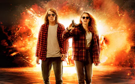 HD PC desktop wallpaper featuring Kristen Stewart and a male co-star from the movie American Ultra, set against a fiery explosion background.