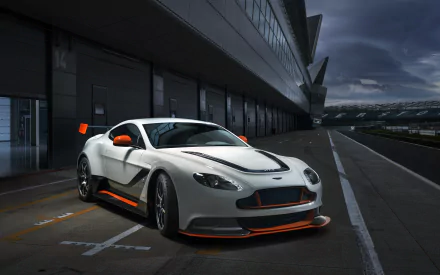 2K Quad HD PC desktop wallpaper background showing a white Aston Martin Vantage GT3 vehicle in a pit lane at dusk, with orange accents and aerodynamic racing bodywork.