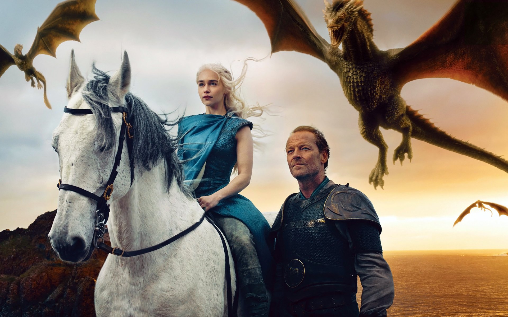 Daenerys Targaryen and Jorah Mormont stand together, with Daenerys on a white horse, as dragons soar above them in a stunning scene from Game of Thrones.