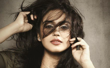 HD PC desktop wallpaper featuring a close-up portrait of woman Huma Qureshi with tousled hair partially covering her face against a textured gray background.