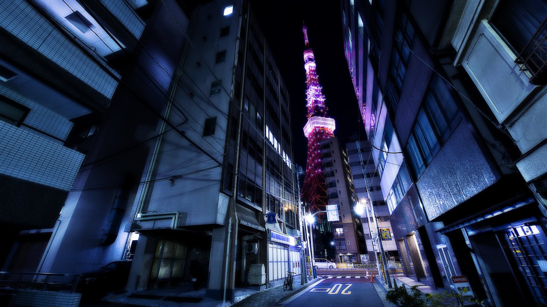 HD desktop wallpaper showcasing a nighttime view of Tokyo's illuminated Tokyo Tower framed by urban buildings on a quiet street.
