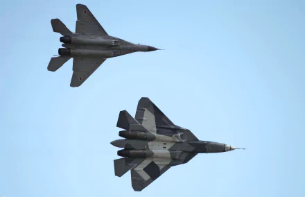 Two advanced military jets, the Mikoyan Gurevich MiG-35 and Sukhoi Su-57, soaring through a clear blue sky, showcased in a vibrant HD desktop wallpaper.