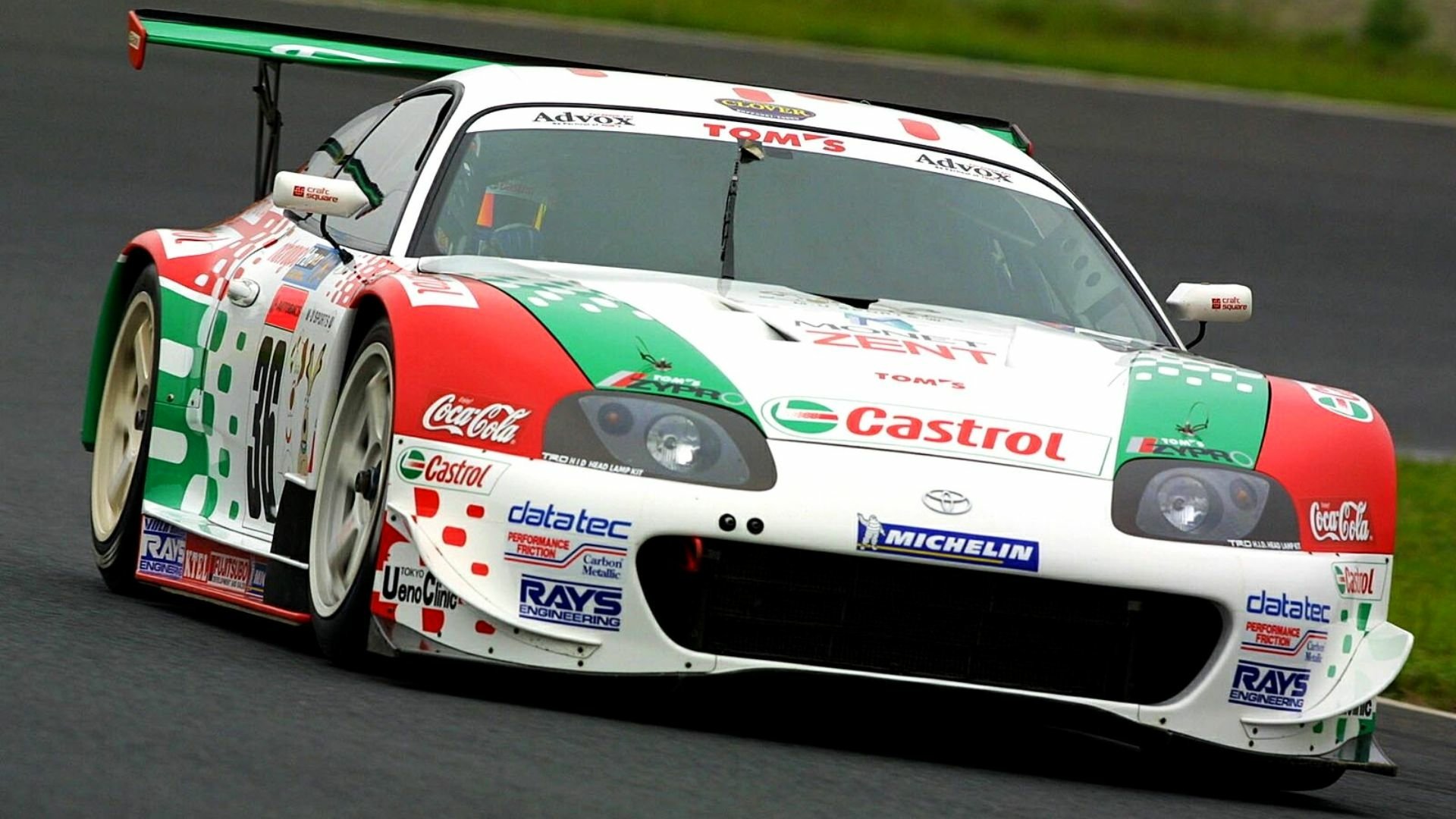 HD PC desktop wallpaper of a Toyota Supra race car featuring Castrol and Coca-Cola branding, speeding on a racetrack with a green and white livery.