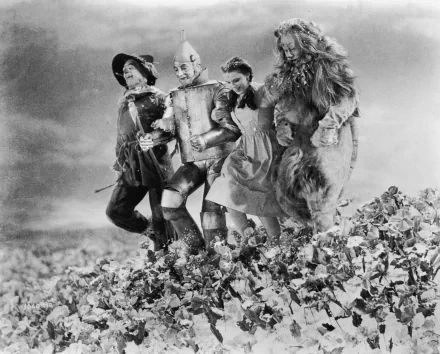Black-and-white HD PC desktop wallpaper from The Wizard of Oz (1939): Dorothy walking arm-in-arm with the Scarecrow, Tin Man and Cowardly Lion across a field.