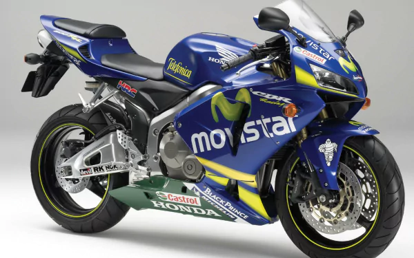 A vibrant Honda CBR motorcycle with a blue and green design, featuring sponsor logos, set against a neutral background, making an impactful HD desktop wallpaper.