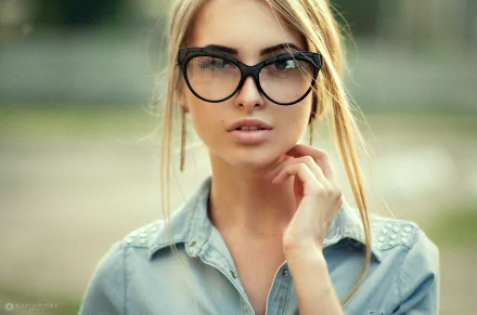 HD desktop wallpaper featuring a close-up of a woman model wearing large black glasses and a denim shirt, with a blurred natural background.