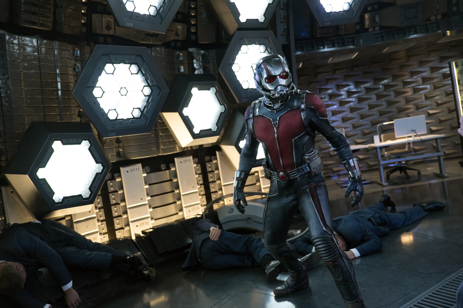 Ant-Man stands in a high-tech room with fallen foes around him, showcased in a 4K Ultra HD PC desktop wallpaper from the Ant-Man movie.