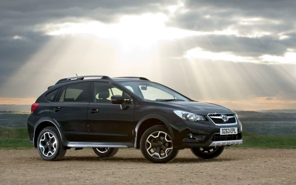 HD wallpaper featuring a Subaru Crosstrek parked outdoors with crepuscular rays beaming through the clouds.
