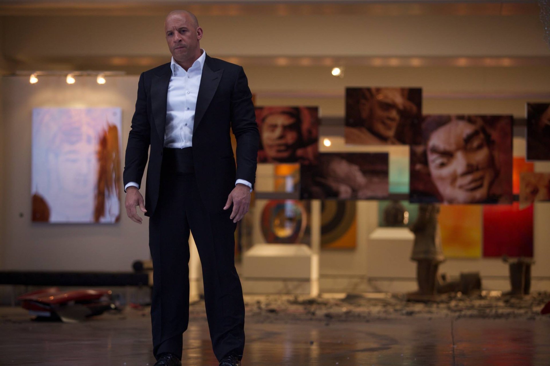 Dominic Toretto, portrayed by Vin Diesel, stands confidently in a sleek suit amidst modern art in this HD wallpaper from the movie Furious 7.