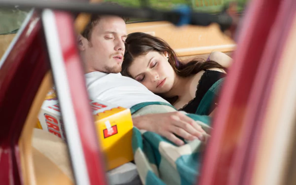 HD wallpaper featuring Anton Yelchin and Alexandra Daddario in a tender moment from the movie Burying the Ex, showcasing their intimate connection while resting together.