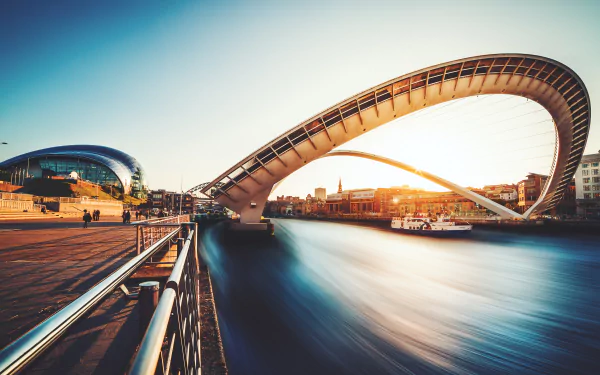 4K Ultra HD view of a man-made bridge arching over a river in Newcastle at sunset, blending modern architecture with serene water reflections.